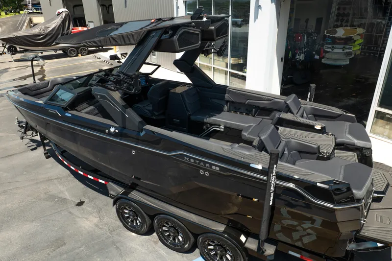 Slide: The Image of 2026 MasterCraft XStar 25 boat on trailer, sleek black design, parked outside showroom. - 9