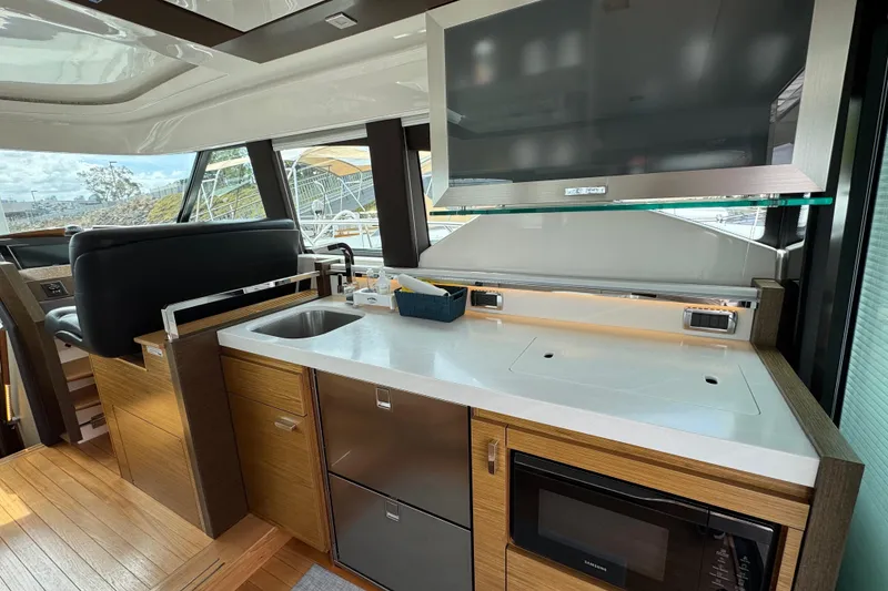 Slide: The Image of Modern kitchen area inside a 2018 Tiara Yachts C44 Coupe, featuring sleek appliances and wood cabinetry. - 16