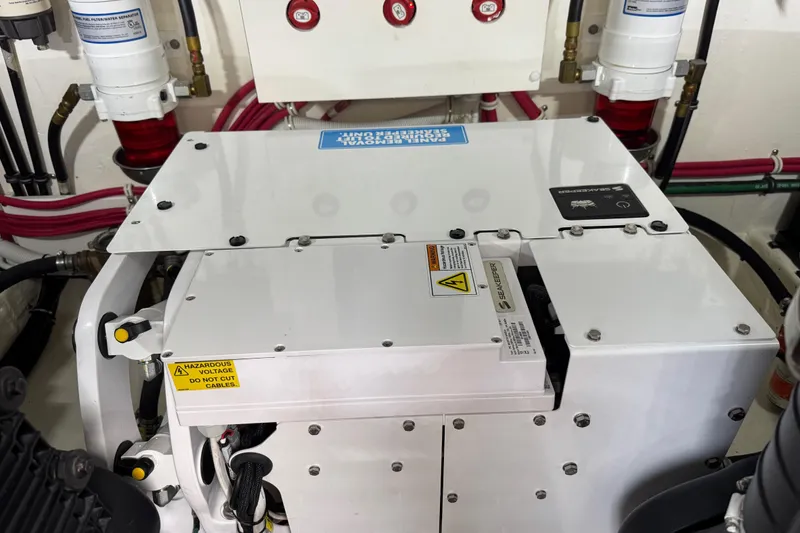 Slide: The Image of Engine room of 2018 Tiara Yachts C44 Coupe with electrical components and warning labels. - 34