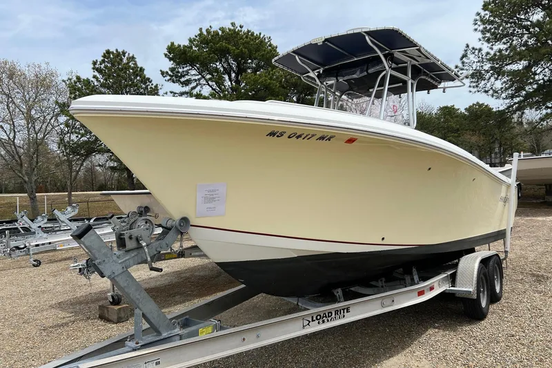 The Image of 2008 Sailfish 2360 CC boat on trailer, parked outdoors with trees in background. - 0