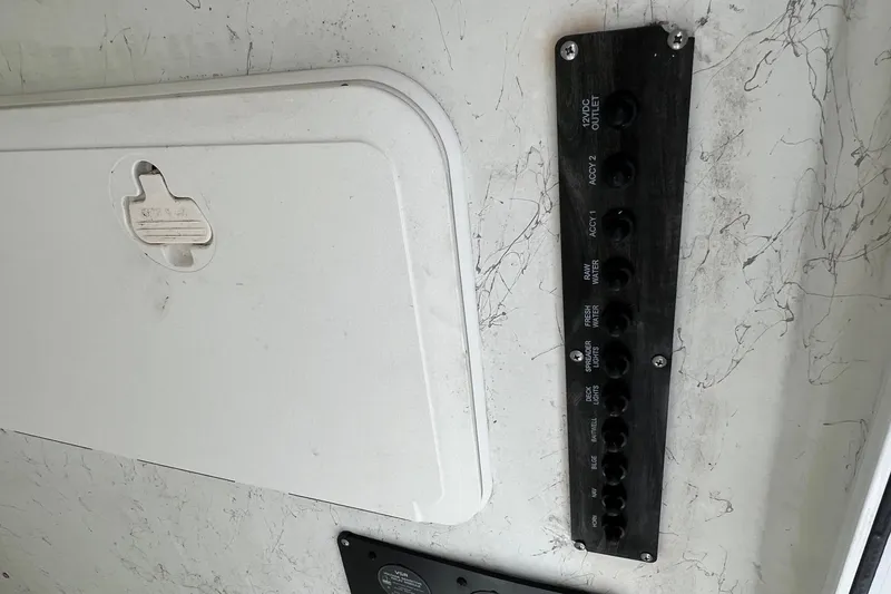 Slide: The Image of Control panel on a 2008 Sailfish 2360 CC boat, featuring various switches and a storage compartment. - 13