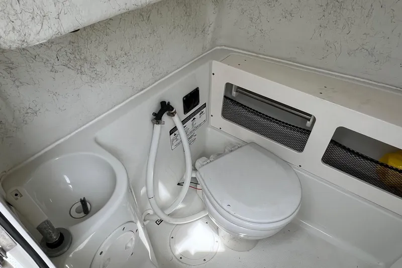 Slide: The Image of Interior of 2008 Sailfish 2360 CC boat featuring compact marine toilet and sink. - 14