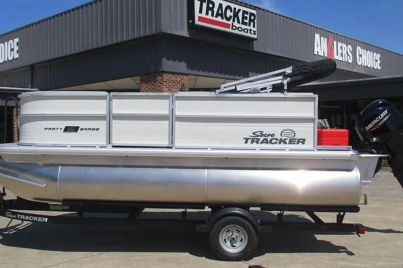 The Image of 2026 Sun Tracker Party Barge 16 DLX pontoon boat on trailer outside dealership. - 1