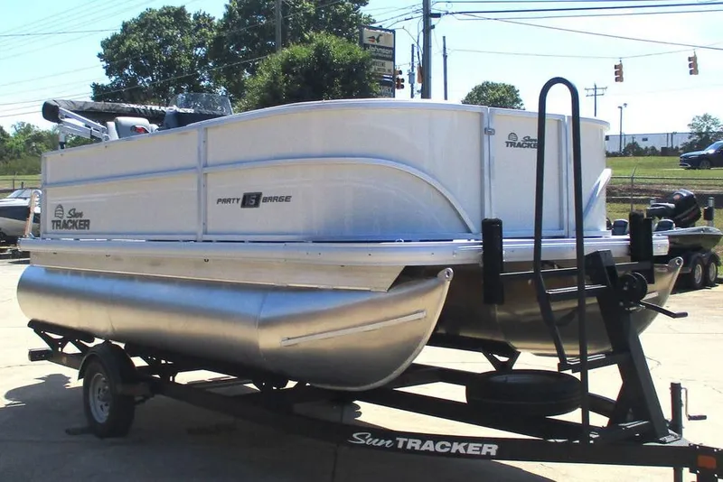 Slide: The Image of 2026 Sun Tracker Party Barge 16 DLX pontoon boat on trailer, parked outdoors. - 14