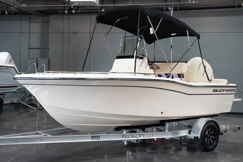Slide: The Image of 2025 Grady-White Fisherman 180 boat on trailer in showroom, featuring sleek design and canopy. - 6
