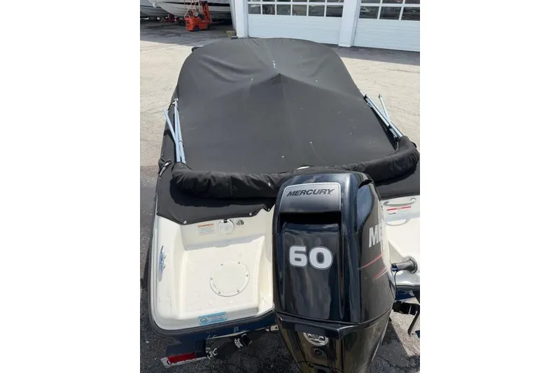 Slide: The Image of 2017 Bayliner 160 Bowrider with Mercury 60 engine, covered and parked outdoors. - 12
