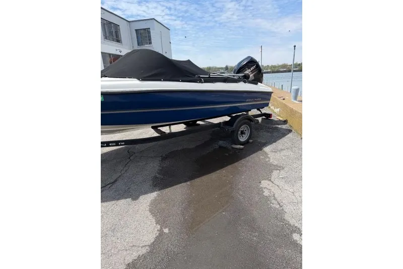 Slide: The Image of 2017 Bayliner 160 Bowrider boat on trailer, covered, near waterfront. - 16