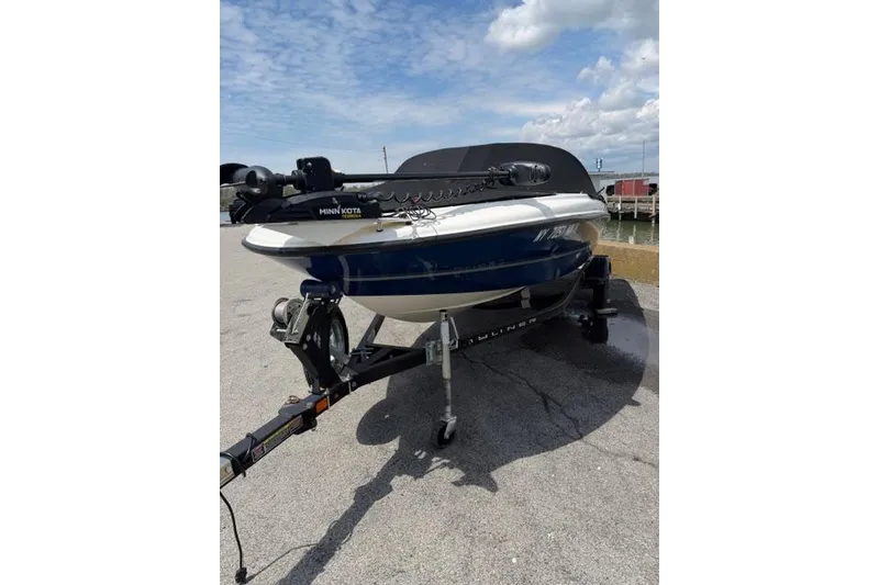 Slide: The Image of 2017 Bayliner 160 Bowrider on trailer, parked near waterfront under cloudy sky. - 2