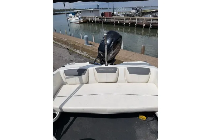 Slide: The Image of 2017 Bayliner 160 Bowrider boat with outboard motor docked by the water. - 6
