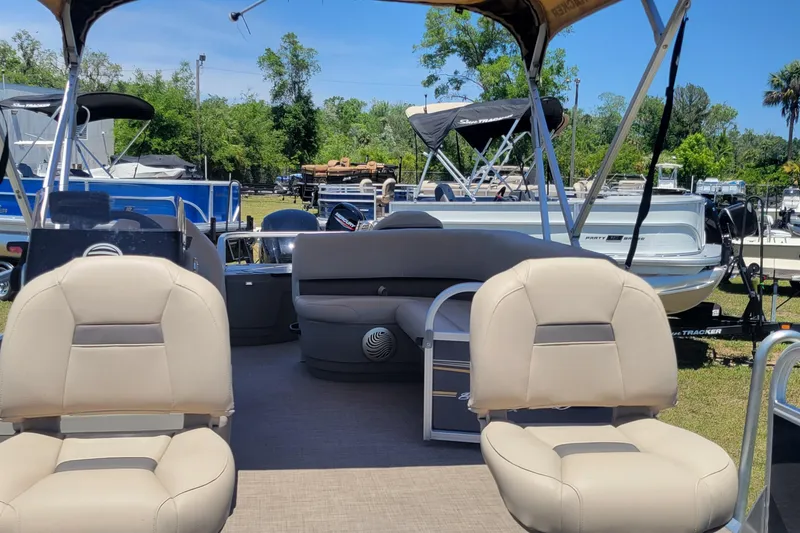 Slide: The Image of 2023 Sun Tracker Bass Buggy 18 DLX pontoon boat with beige seating, parked outdoors. - 13