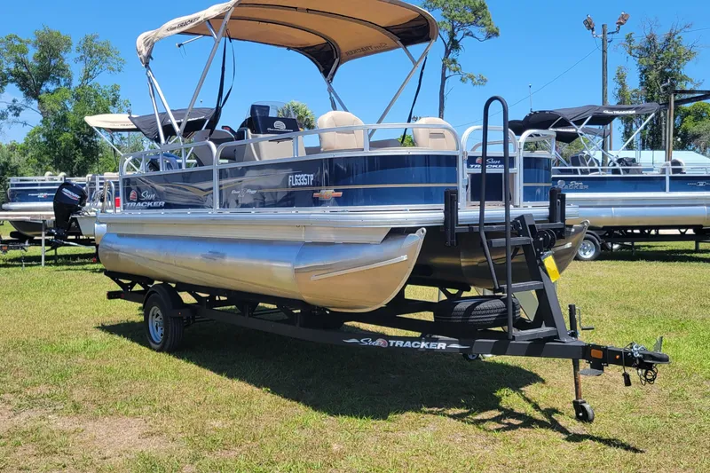Slide: The Image of 2023 Sun Tracker Bass Buggy 18 DLX pontoon boat on trailer, parked on grass. - 6