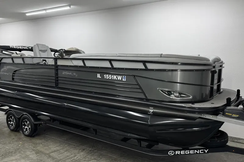 Slide: The Image of 2017 Regency 254 LE3 pontoon boat in a garage, sleek design, black and gray color scheme. - 2