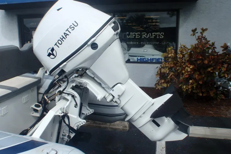Slide: The Image of Tohatsu outboard motor on a 2022 Highfield Classic 360 GT boat, parked near a shop. - 7