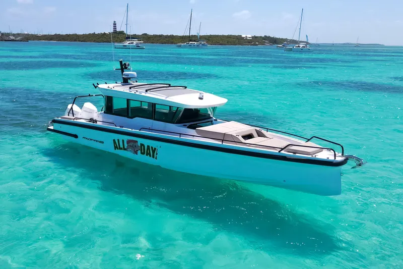 The Image of 2025 Axopar 37 XC Cross Cabin boat on turquoise water, near a scenic coastline. - 0