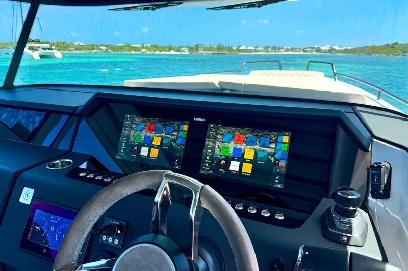 Slide: The Image of 2025 Axopar 37 XC Cross Cabin dashboard with advanced navigation screens, steering wheel, and ocean view. - 9