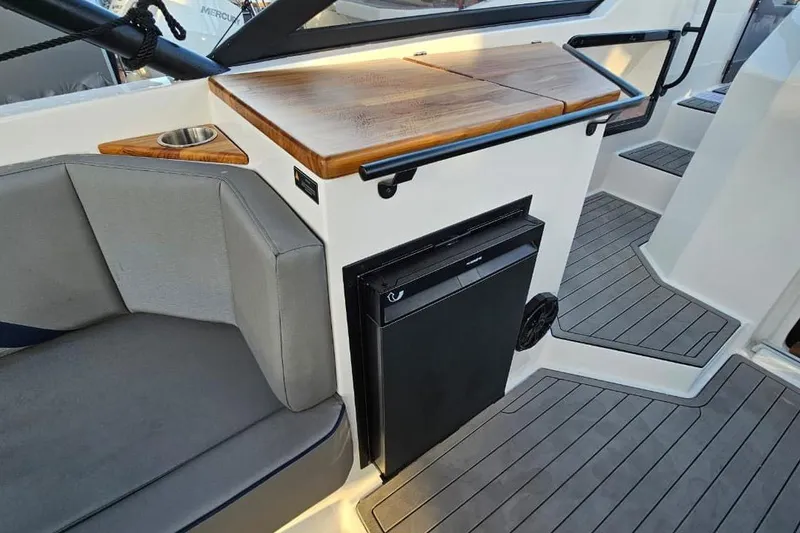 Slide: The Image of Interior of 2027 Hanover 327 boat with seating, wooden countertop, and built-in refrigerator. - 10