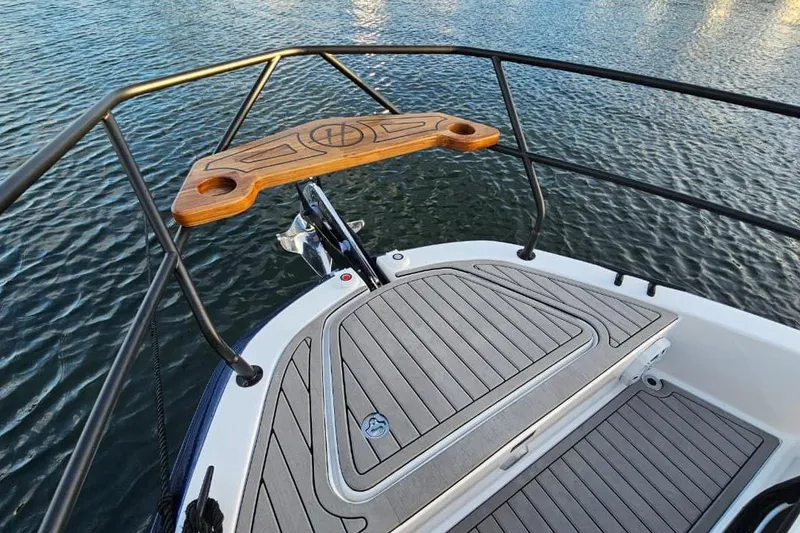 Slide: The Image of Bow view of 2027 Hanover 327 boat with teak deck and railing over water. - 25