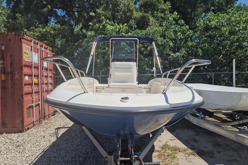 Slide: The Image of 2017 Bayliner Element F18 boat on trailer, parked outdoors near shipping container. - 19