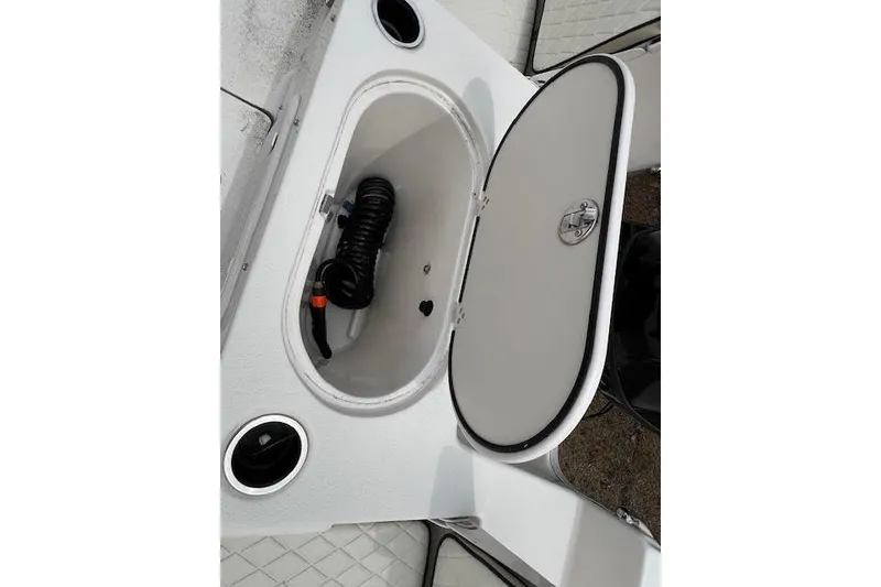 Slide: The Image of Open storage compartment on 2020 Carolina Skiff 25 LS boat, featuring coiled hose. - 7