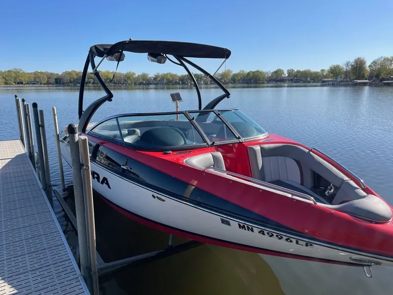 The Image of 2011 Supra Sunsport boat docked on a calm lake. - 0