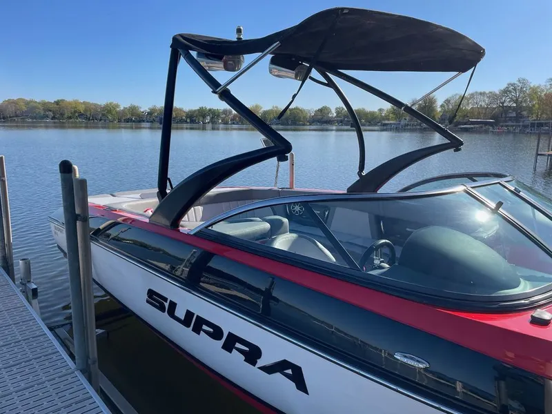 Slide: The Image of 2011 Supra Sunsport boat docked on a calm lake. - 6