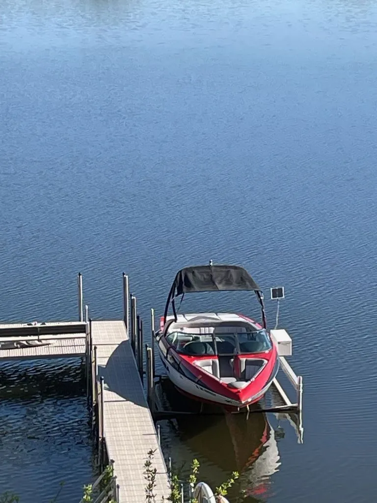 Slide: The Image of 2011 Supra Sunsport boat docked on calm water. - 7