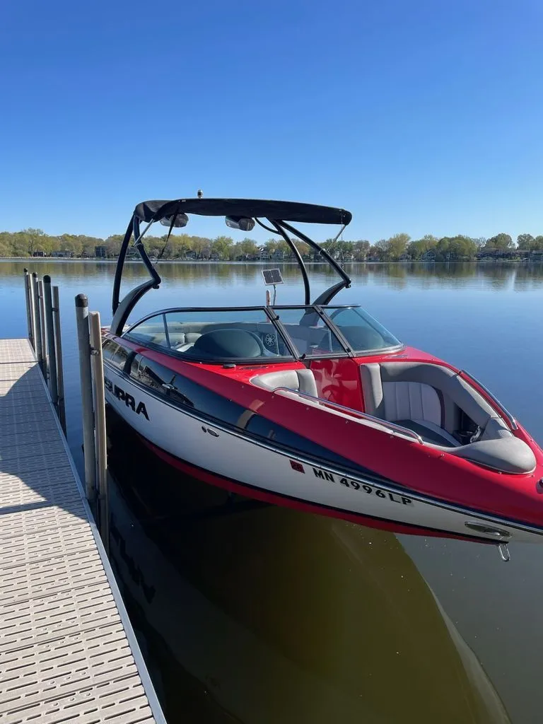 Slide: The Image of 2011 Supra Sunsport boat docked on a calm lake. - 8