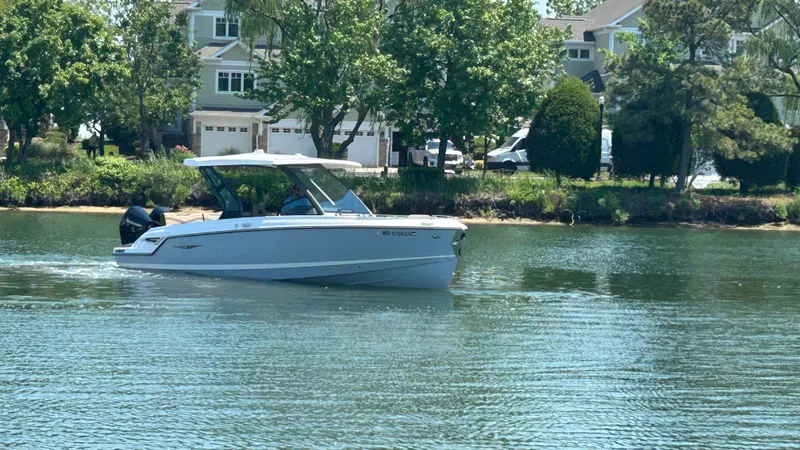 Slide: The Image of 2025 Monterey Elite 30 OB boat on calm water near houses. - 0