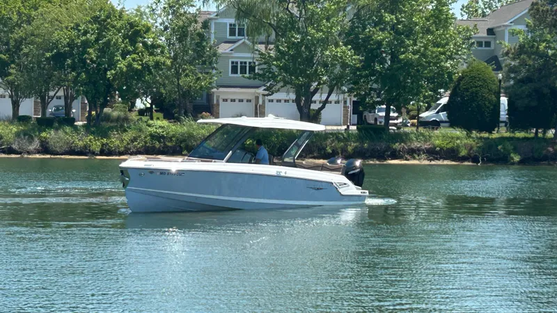 Slide: The Image of 2025 Monterey Elite 30 OB boat on calm water near houses. - 6