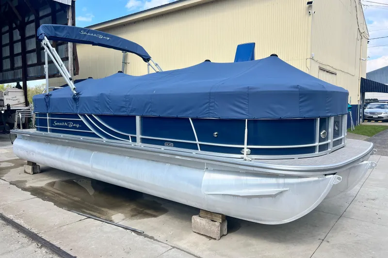 Slide: The Image of 2023 South Bay 224 RS pontoon boat with blue cover, docked outdoors. - 4