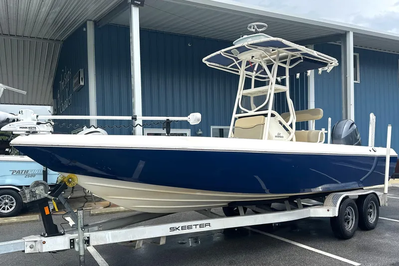 The Image of 2014 Skeeter SX2250 boat on trailer, blue hull, parked under a metal canopy. - 2