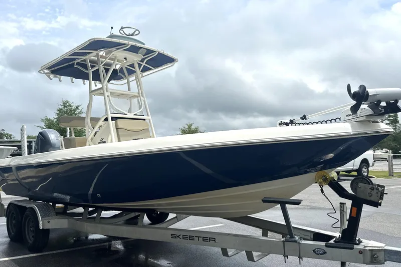 Slide: The Image of 2014 Skeeter SX2250 boat on trailer, featuring blue hull and T-top, parked outdoors. - 6