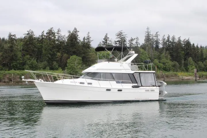 Slide: The Image of 1992 Bayliner 3288 Motoryacht cruising on a serene lake with forested shoreline. - 2