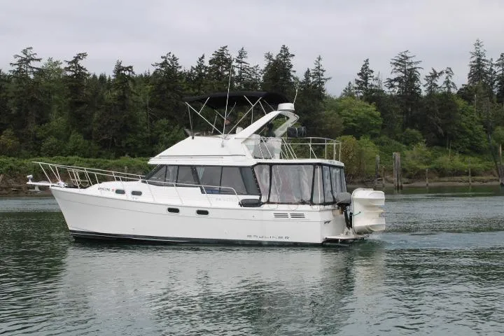 Slide: The Image of 1992 Bayliner 3288 Motoryacht cruising on a calm lake with forested shoreline. - 3