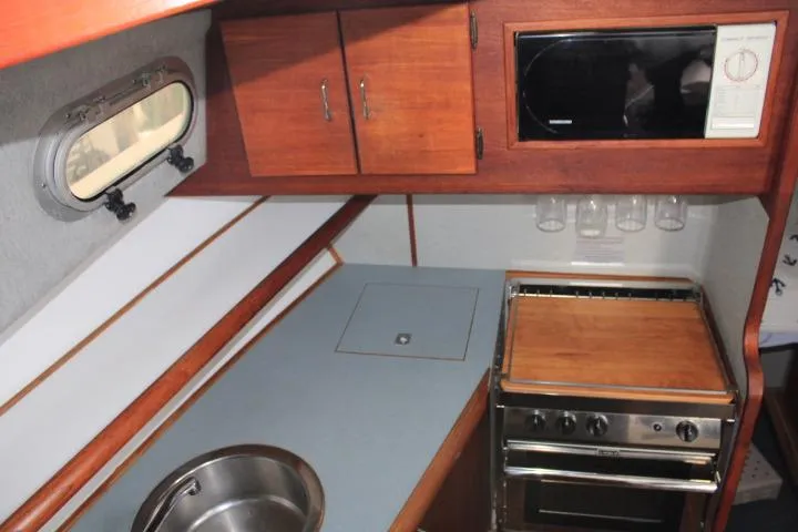 Slide: The Image of 1992 Bayliner 3288 Motoryacht kitchen with sink, stove, microwave, and wooden cabinets. - 37