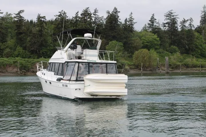 Slide: The Image of 1992 Bayliner 3288 Motoryacht cruising on a serene river with lush forest backdrop. - 4