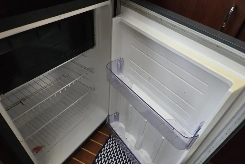 Slide: The Image of Empty refrigerator inside a 1992 Bayliner 3288 Motoryacht, featuring wire shelves and door storage. - 40