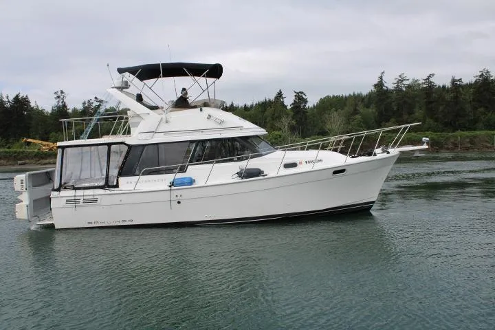 Slide: The Image of 1992 Bayliner 3288 Motoryacht cruising on a calm lake with forested shoreline. - 7
