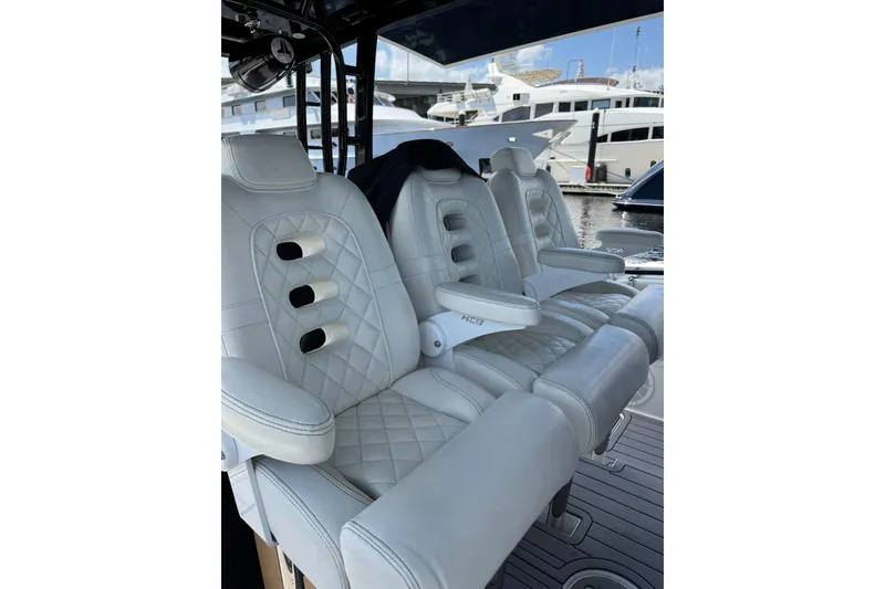 Slide: The Image of Luxurious white seating on a 2019 HCB 42 Siesta boat, docked with yachts in the background. - 14