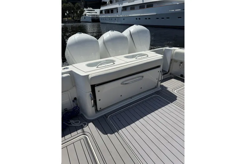 Slide: The Image of 2019 HCB 42 Siesta boat deck with triple outboard engines, docked near luxury yachts. - 17