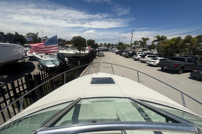 Slide: The Image of 2004 Sea Ray 215 Weekender boat docked, surrounded by parked cars and American flags. - 12