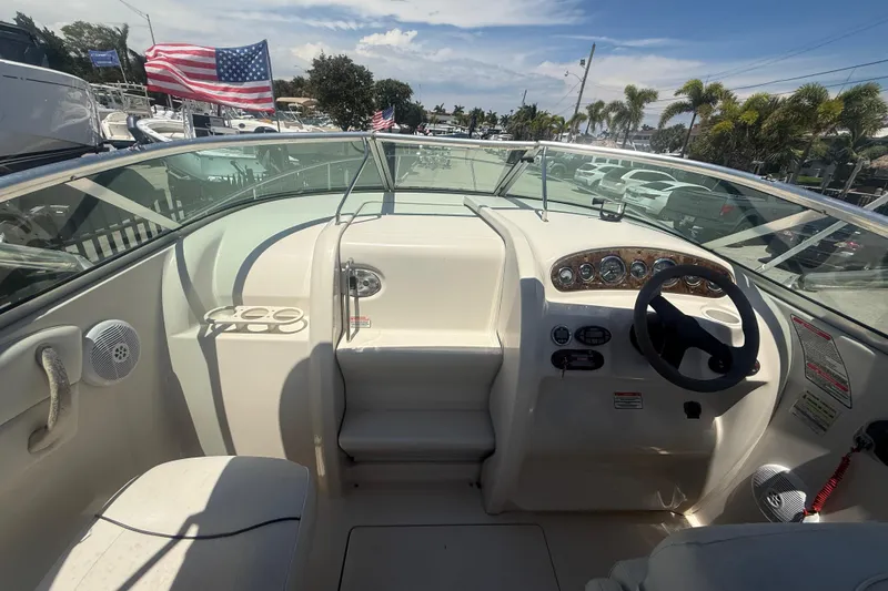 Slide: The Image of 2004 Sea Ray 215 Weekender boat cockpit with steering wheel and dashboard, American flag visible. - 16