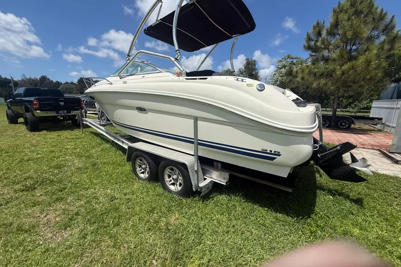 Slide: The Image of 2004 Sea Ray 215 Weekender boat on trailer, parked on grass under a clear blue sky. - 3