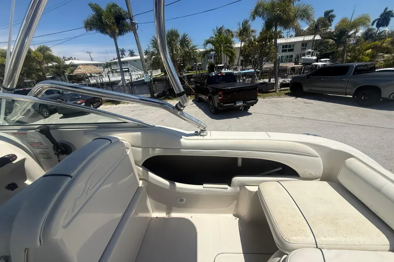 Slide: The Image of 2004 Sea Ray 215 Weekender boat interior with seating, parked near palm trees and vehicles. - 6