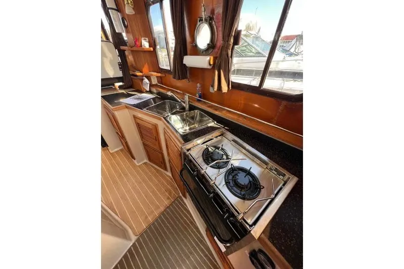 Slide: The Image of 2013 Ranger Tugs R-29 S galley with stove, sink, and wooden cabinetry. - 43