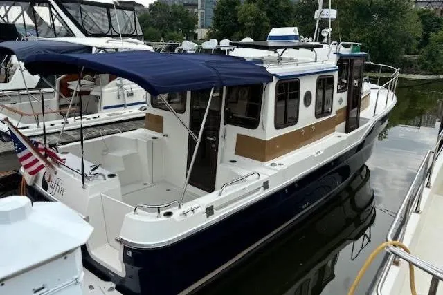 Slide: The Image of 2013 Ranger Tugs R-29 S boat docked, featuring a blue canopy and American flag. - 47