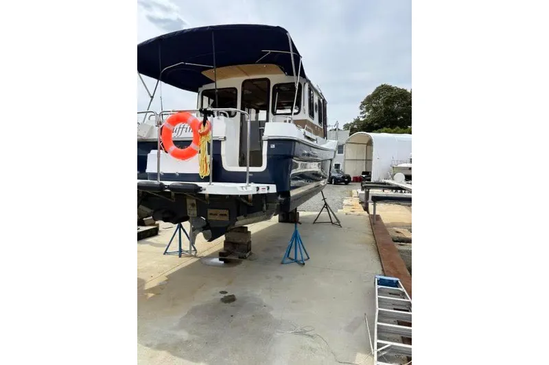 Slide: The Image of 2013 Ranger Tugs R-29 S boat on dry dock with blue canopy and lifebuoy. - 48