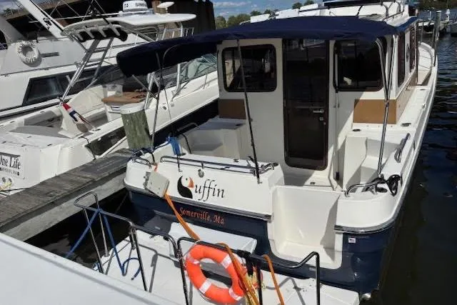 Slide: The Image of 2013 Ranger Tugs R-29 S docked, featuring a spacious deck and canopy. - 6