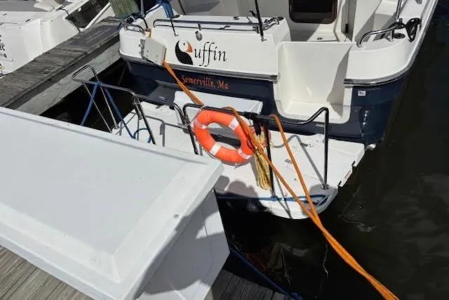 Slide: The Image of 2013 Ranger Tugs R-29 S boat docked, featuring a lifebuoy and orange rope. - 7