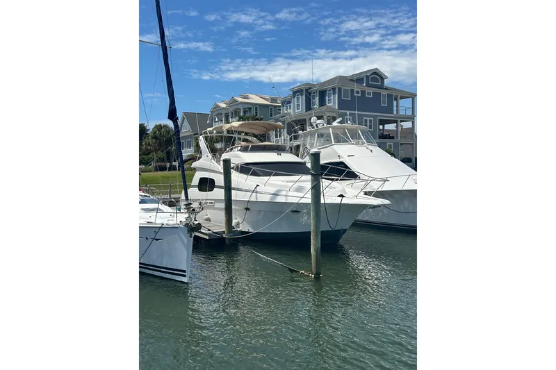 The Image of 2001 Silverton 410 Sport Bridge yacht docked near waterfront homes. - 1